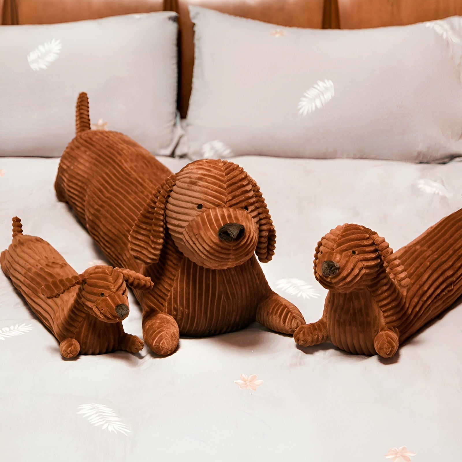 Three brown corduroy dog toys on a white bed