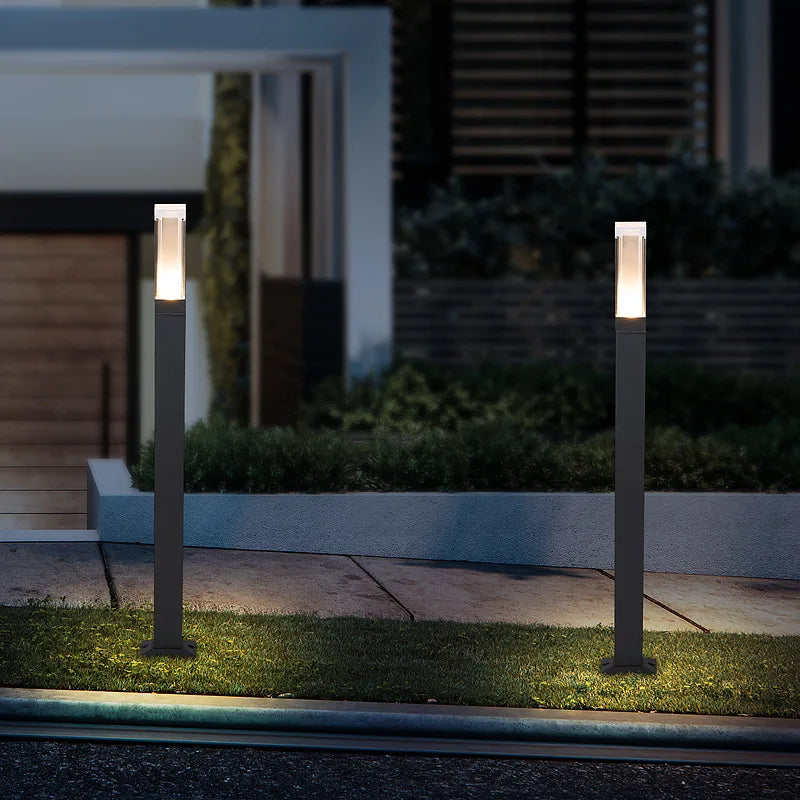 Two outdoor garden lights on posts in a garden setting at night.