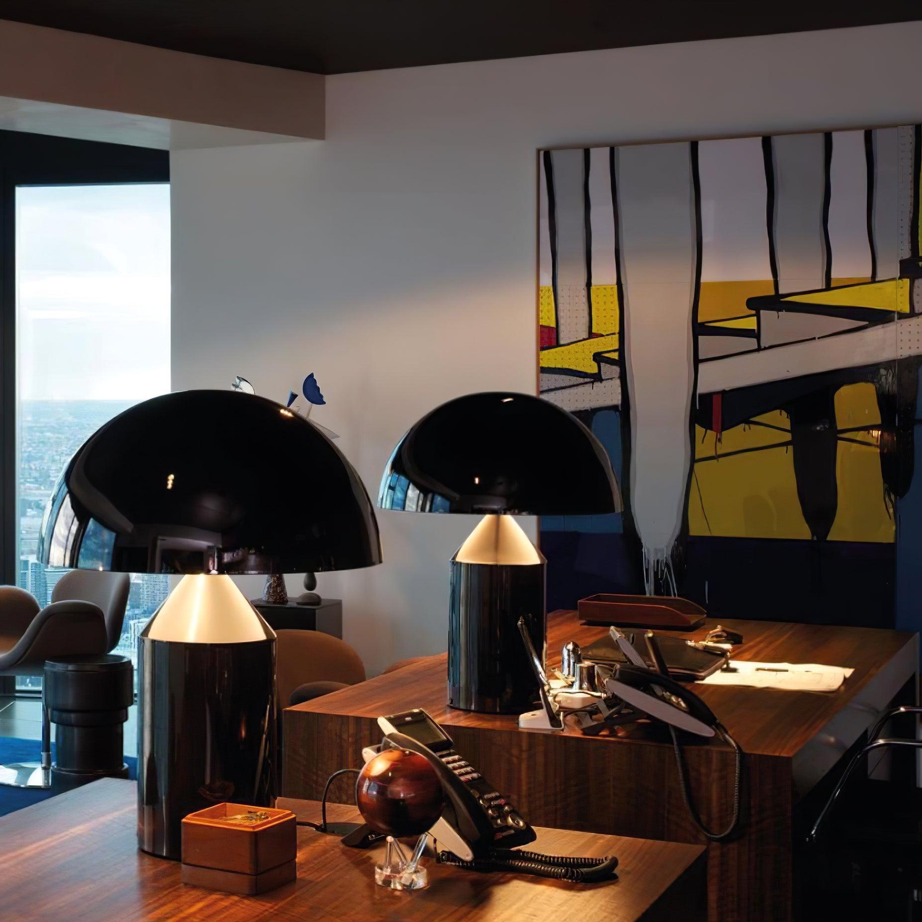 Modern office desk with black table lamps and abstract artwork on the wall.