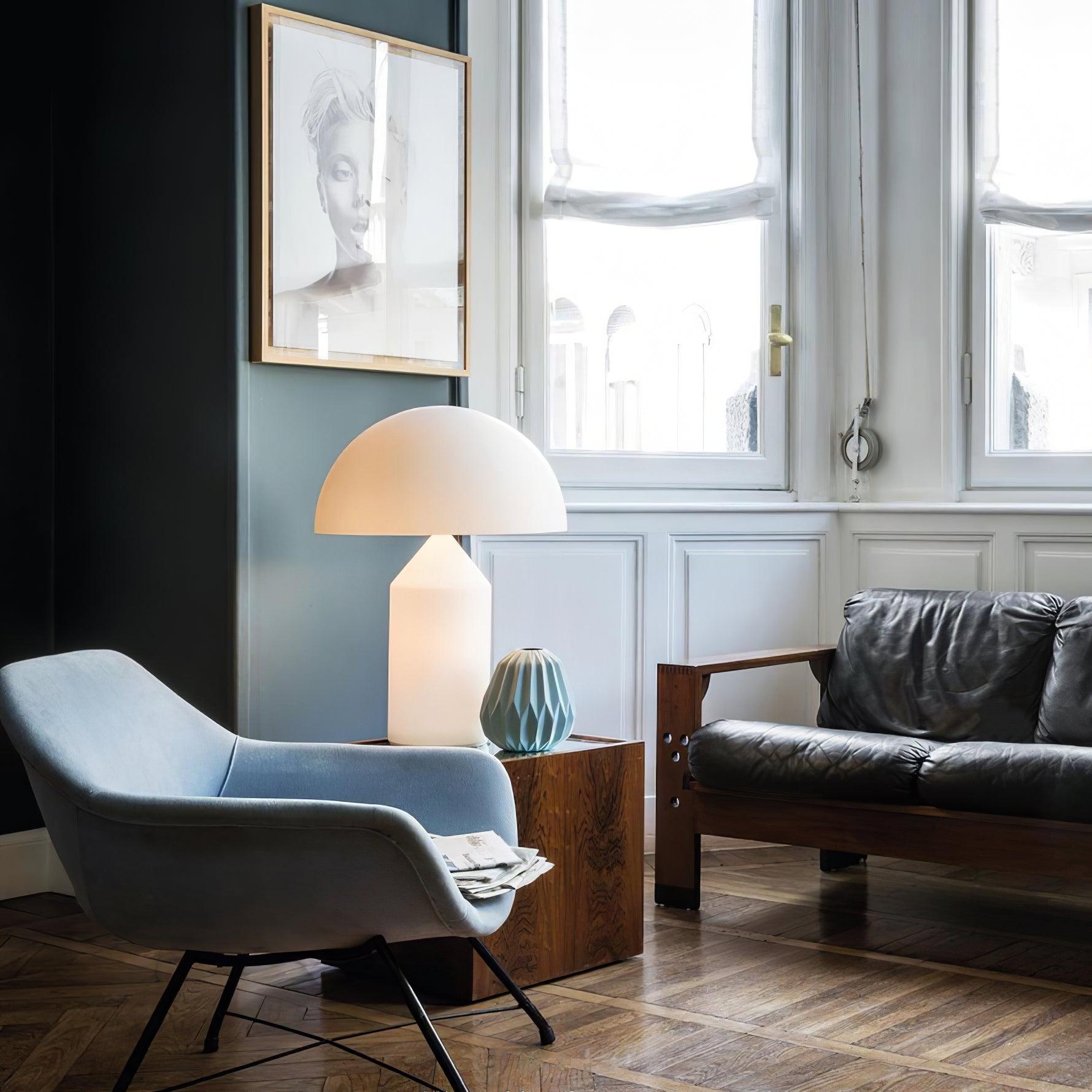 Modern living room with a gray armchair, lamp, and sofa.