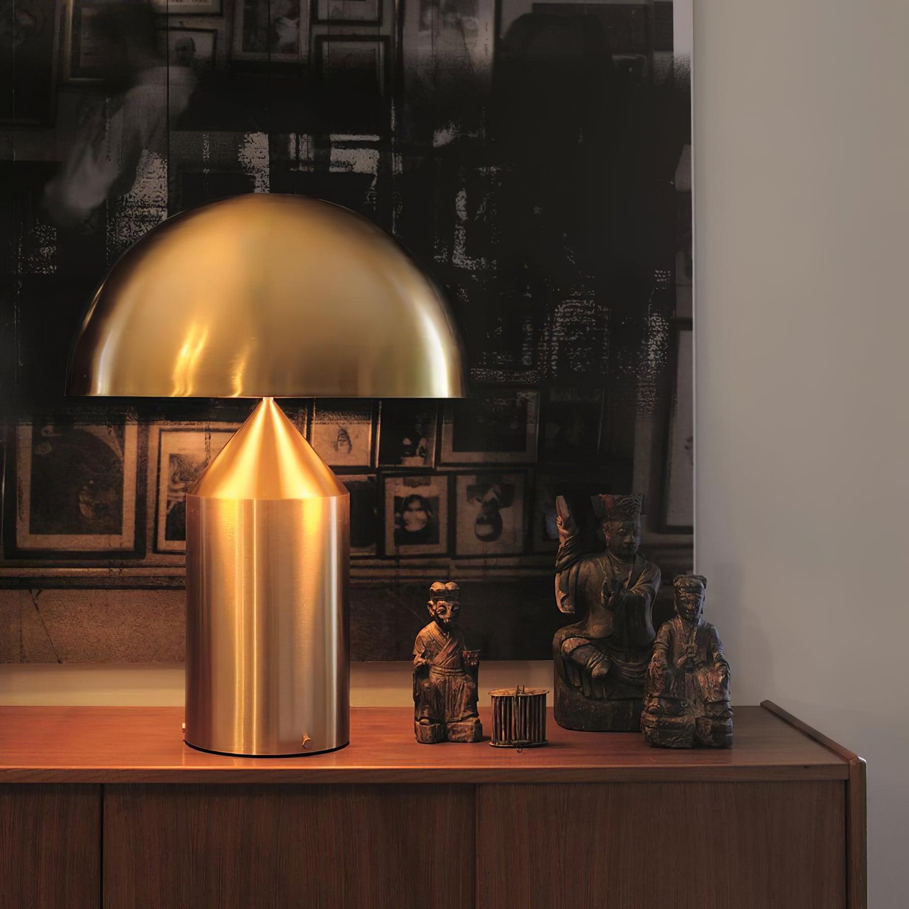 Gold lamp on a wooden surface with framed pictures in the background