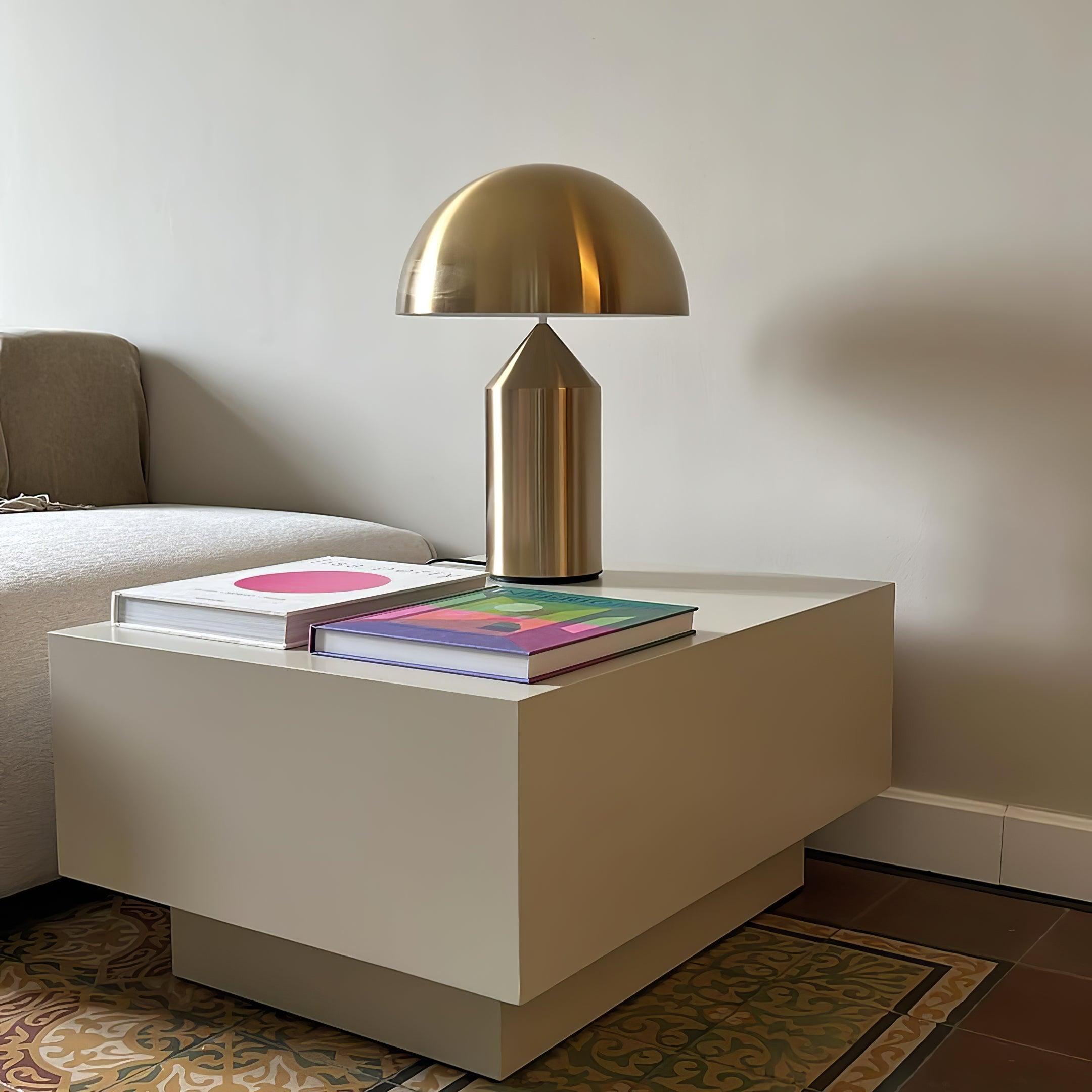 Modern side table with a gold lamp and books in a living room setting.