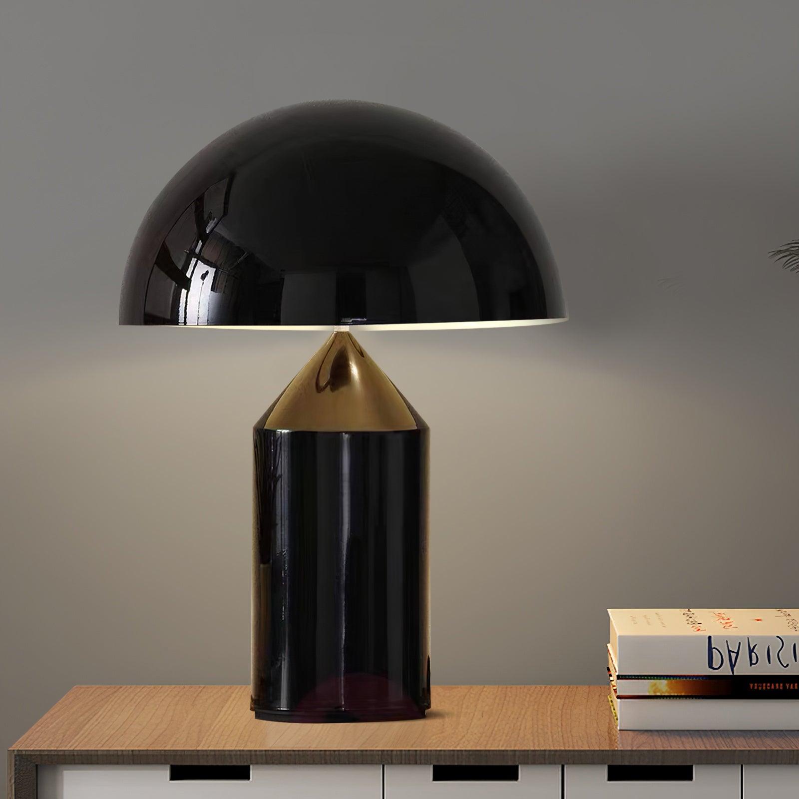Black table lamp with a cone-shaped base on a wooden surface against a gray wall.