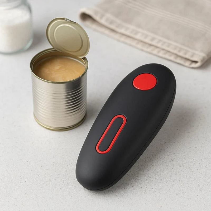 Black can opener with red accents next to an open can on a light surface.