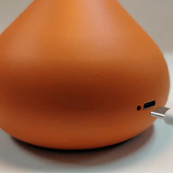 Close-up of an orange electronic device with a USB cable inserted.