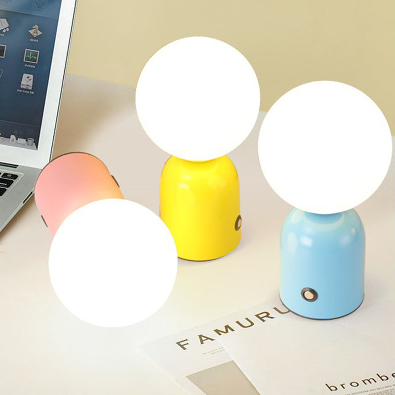 Colorful small round lamps on a desk with a laptop and paper in the background.