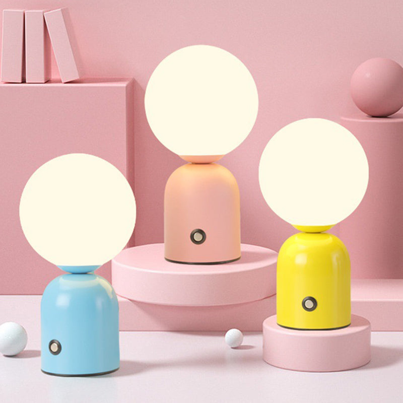 Three colorful table lamps with round white shades on a pink background