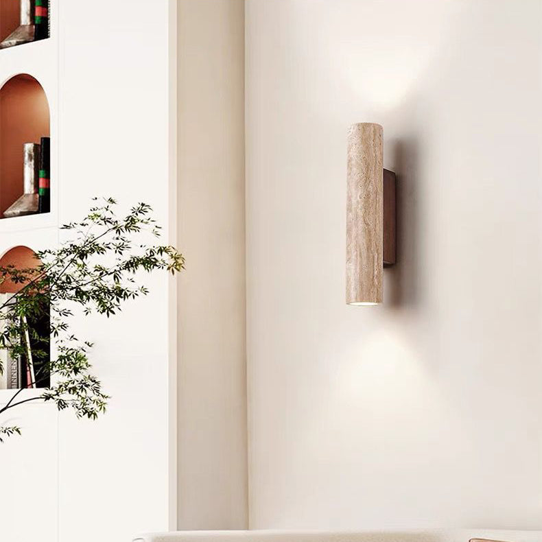 Modern wall-mounted light fixture on a white wall with a plant in the foreground.