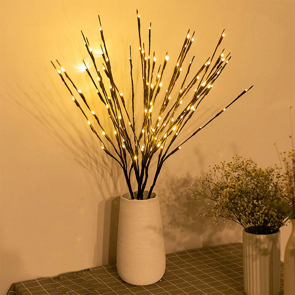 Decorative lighting branch with lights in a white vase on a tiled floor.