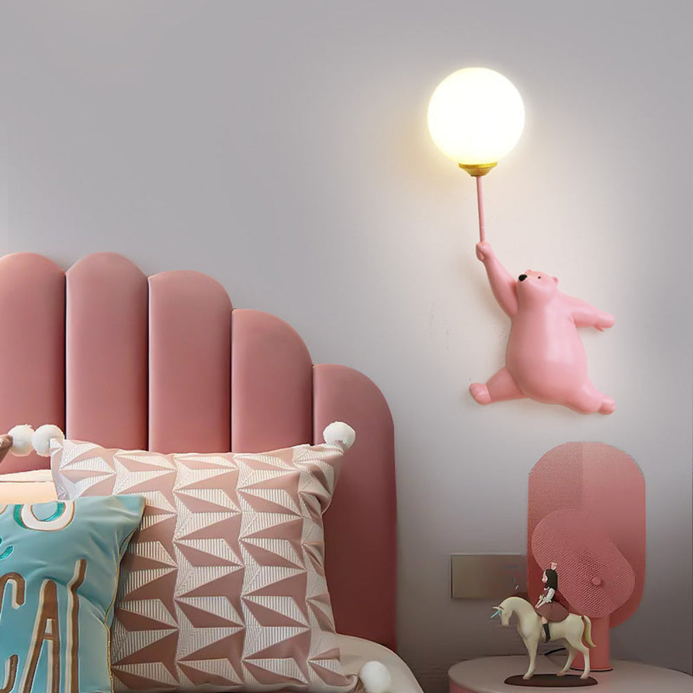 Children's room with pink upholstered chair, decorative pillows, and a wall-mounted light shaped like a bear.