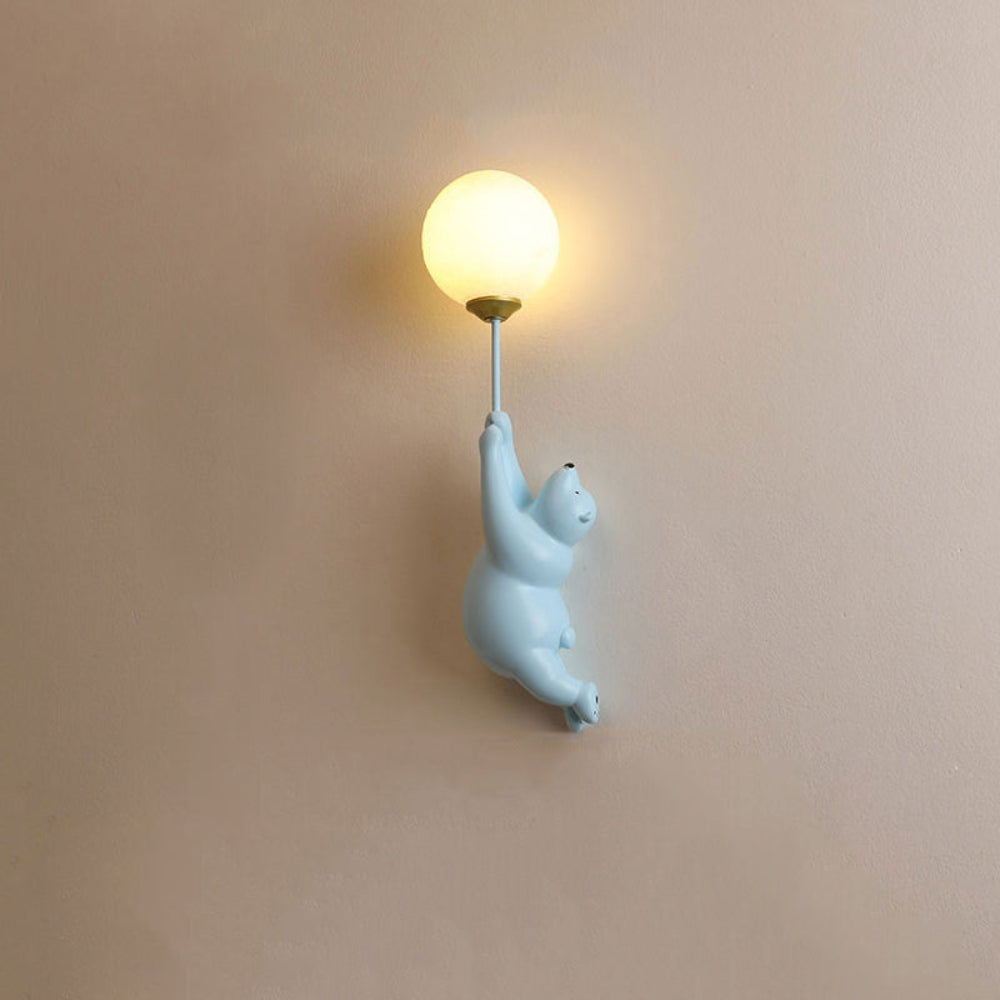 Wall-mounted light fixture with a polar bear design holding a light bulb against a beige wall.