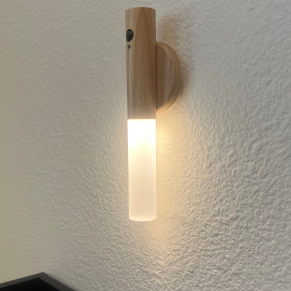 Wooden wall sconce with a light bulb on a textured white wall