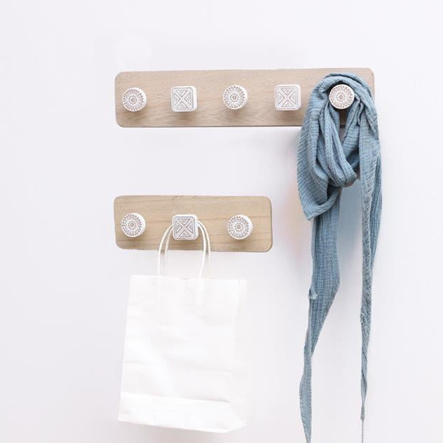 Wooden wall hook with multiple hooks holding a blue scarf and white bag on a white background