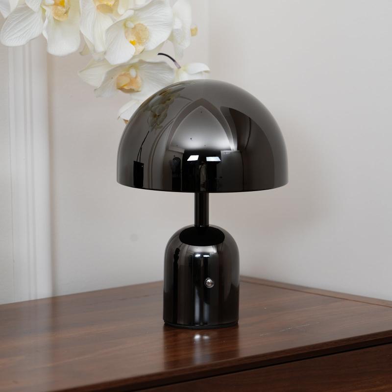 Black table lamp on a wooden surface with a blurred floral background