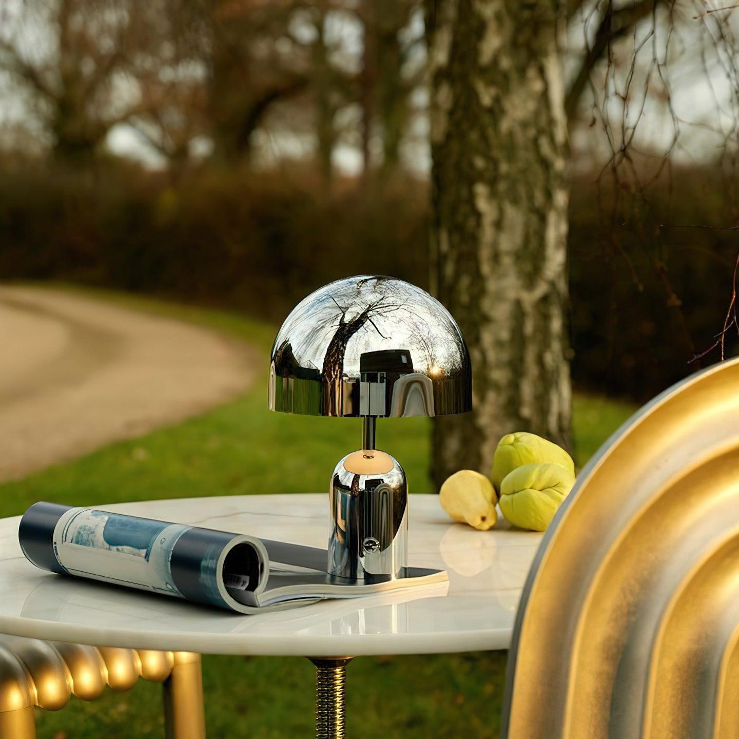 Modern silver table lamp on a table outdoors with a blurred natural background