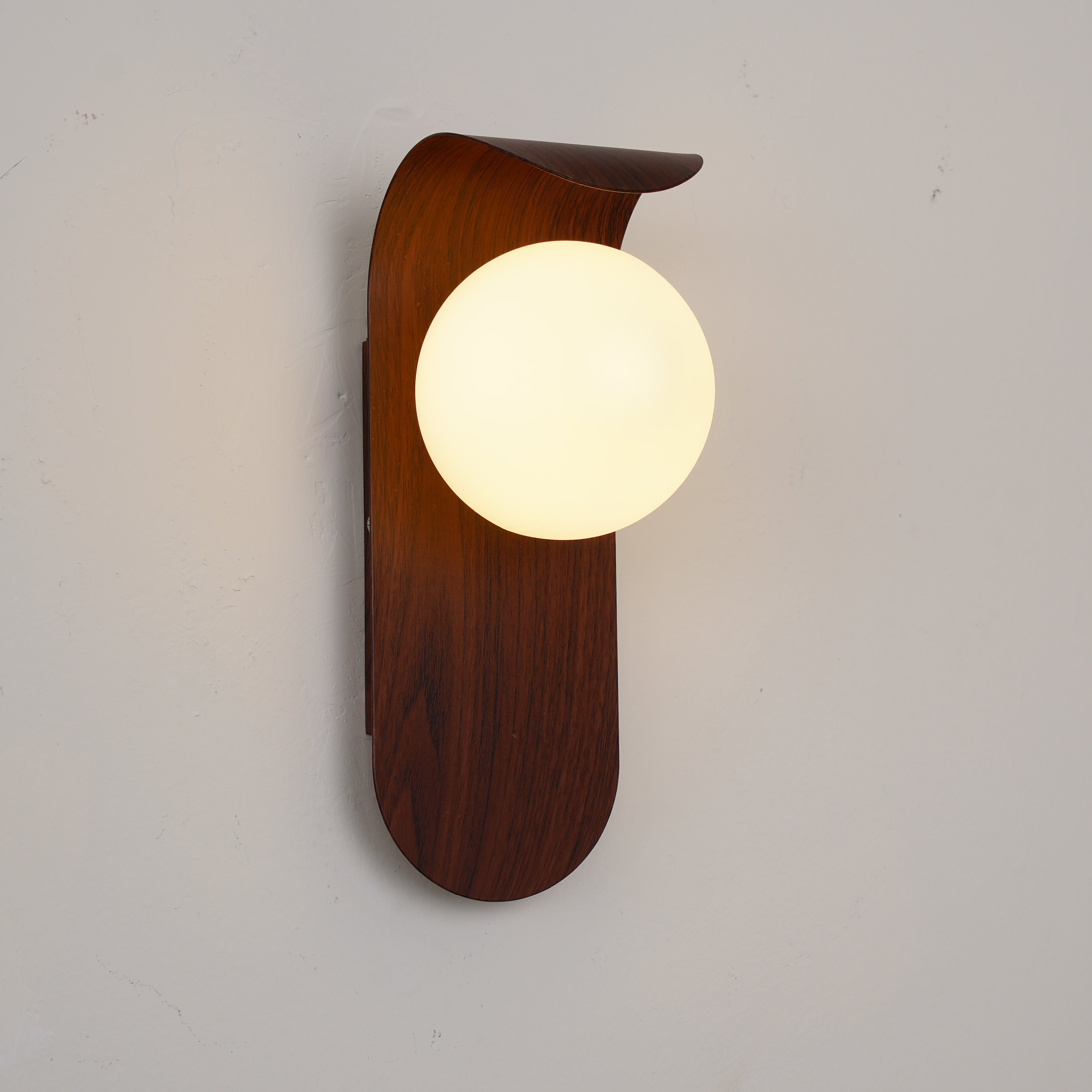 Wooden wall lamp with a round glass shade on a plain background