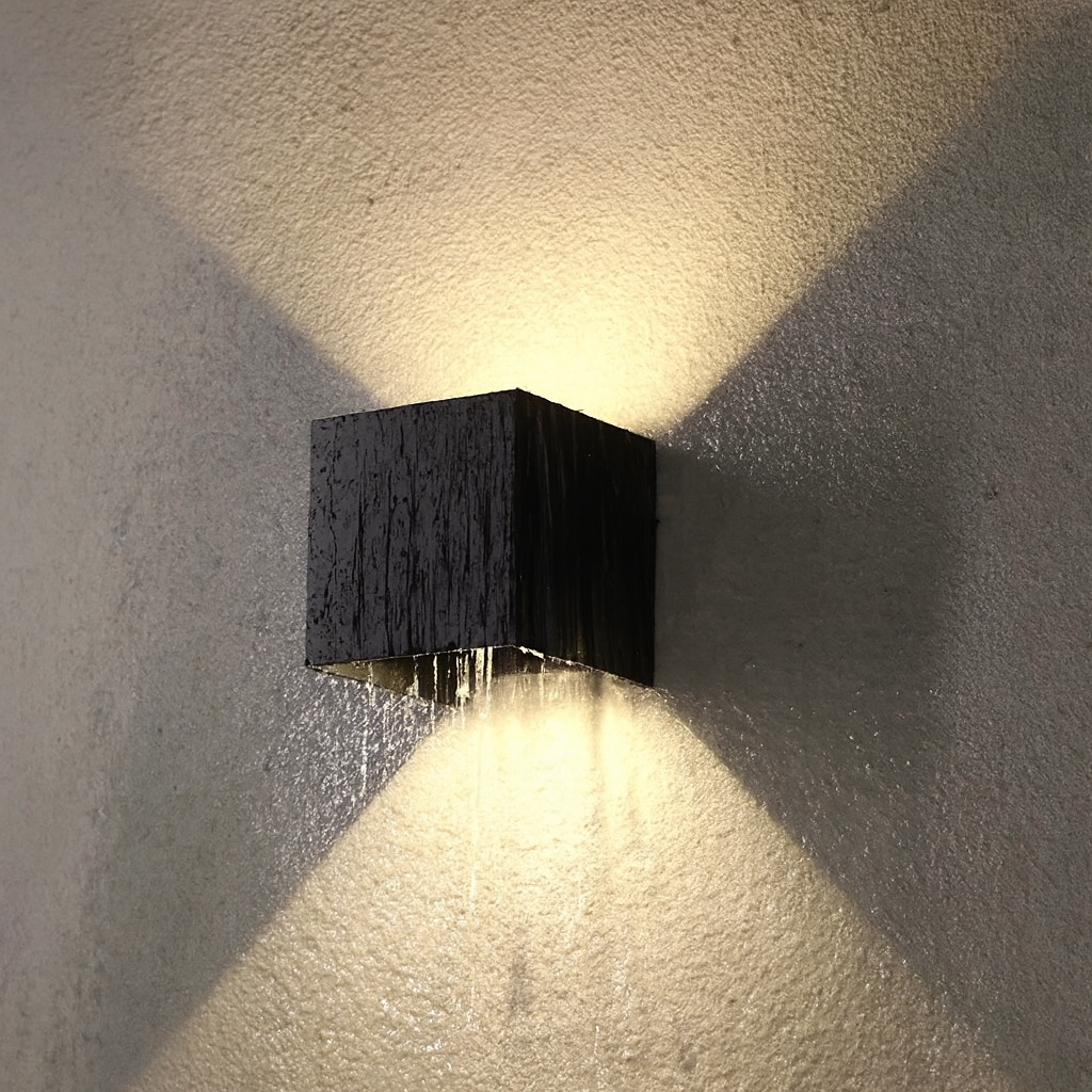 Modern wall-mounted light fixture casting a shadow on a textured wall.