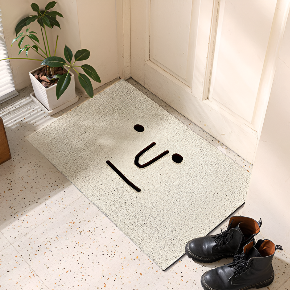 Decorative doormat with abstract black design on a light-colored floor, next to a plant and shoes.