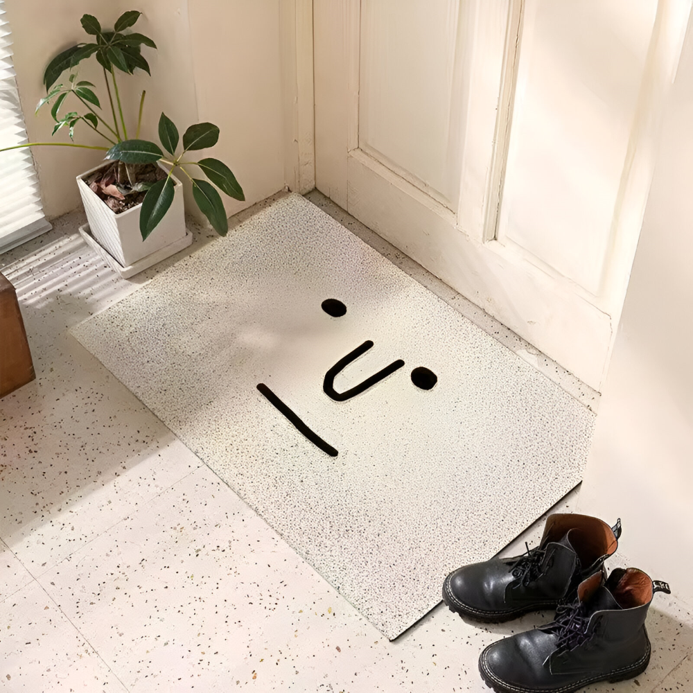 Decorative doormat with abstract design on a light-colored floor next to a plant and shoes.