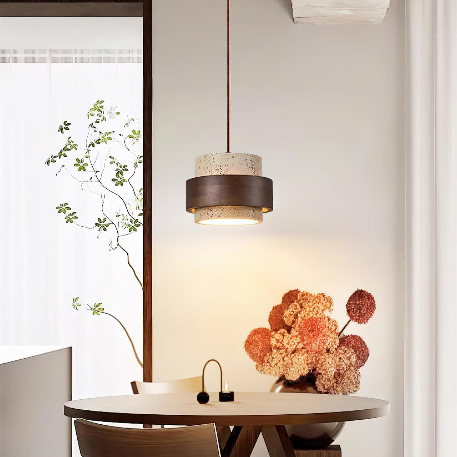 Modern dining area with a round wooden table and chair, pendant light, and decorative flowers.