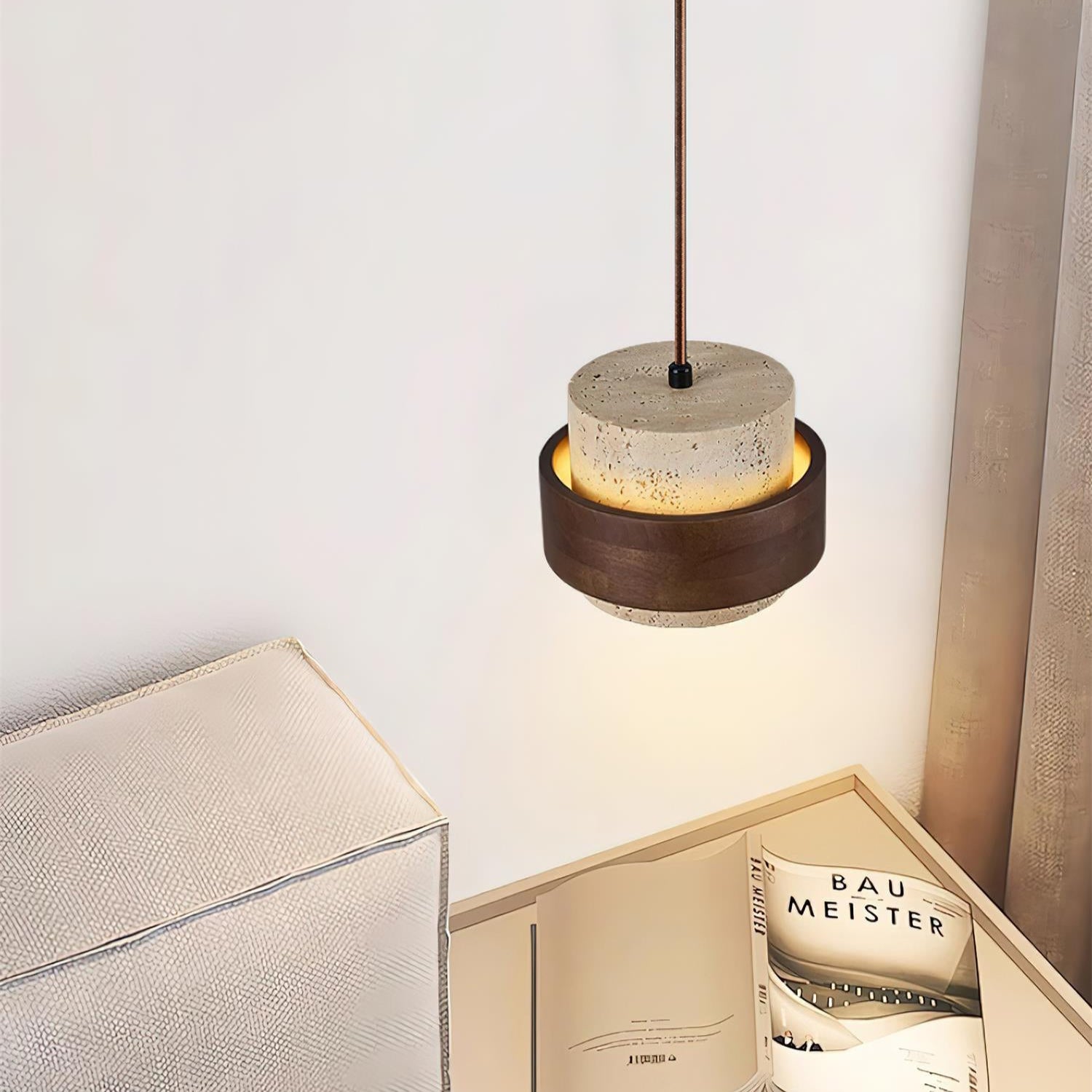 Modern pendant light above a nightstand with a magazine and glass.