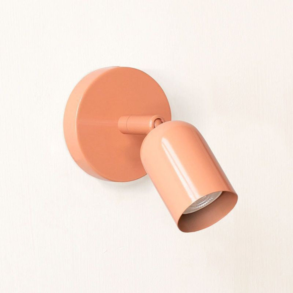 Coral-colored wall light fixture on a white background