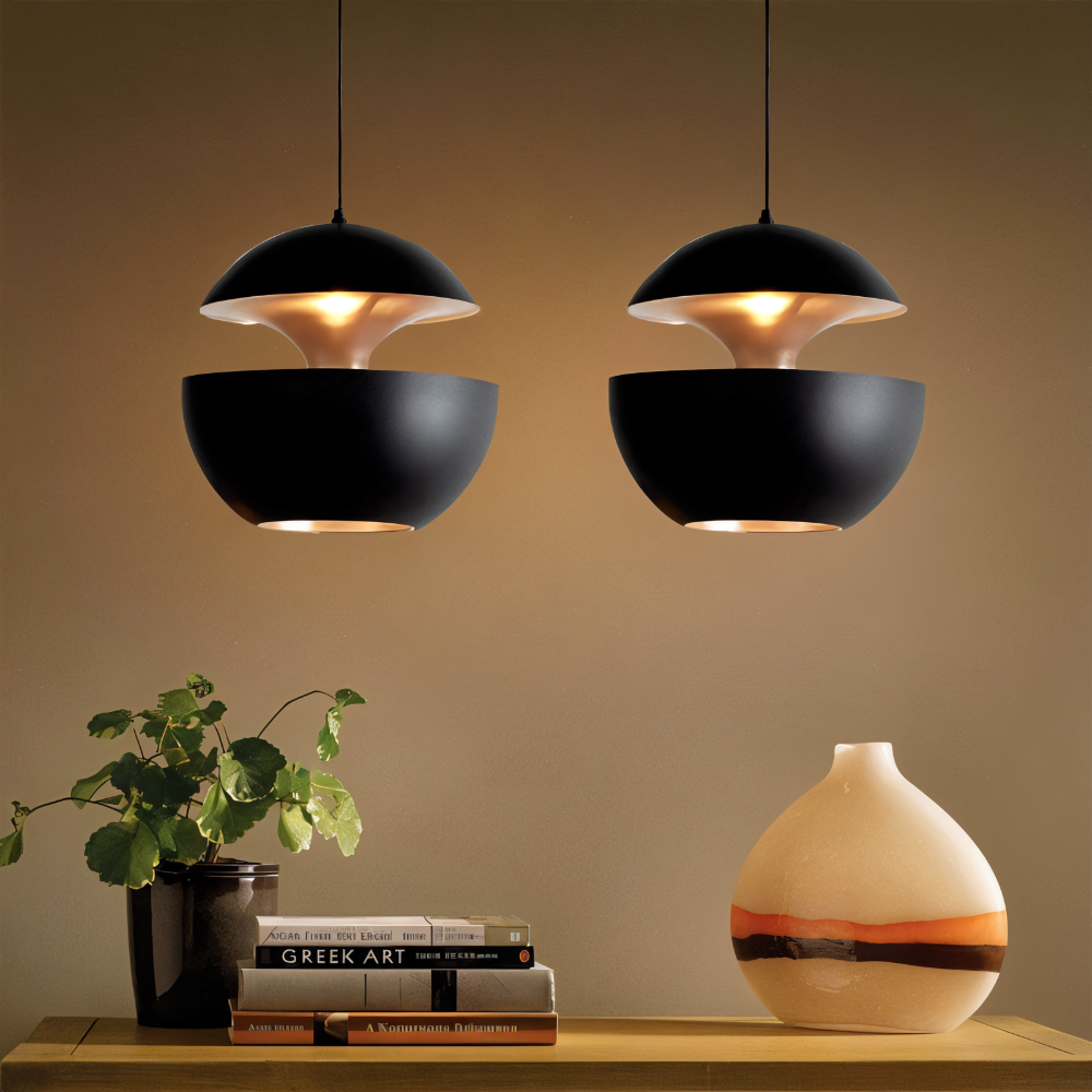 Two black pendant lights hanging above a wooden surface with books and a vase.