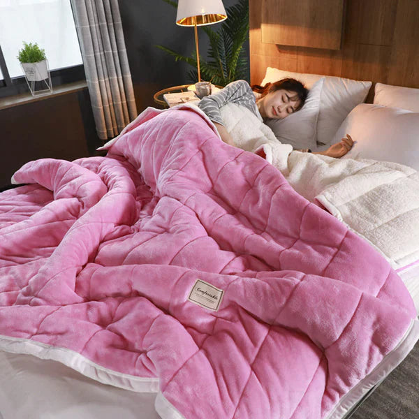 Person lying in bed under a pink weighted blanket in a bedroom setting.