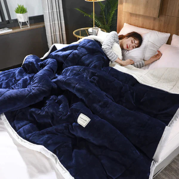 Person lying in bed under a blue blanket with a visible brand label.