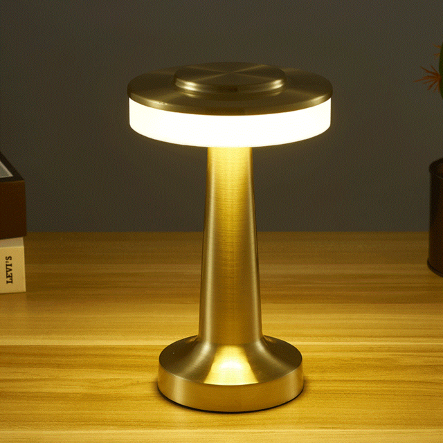 Gold table lamp on a wooden surface with a dark background