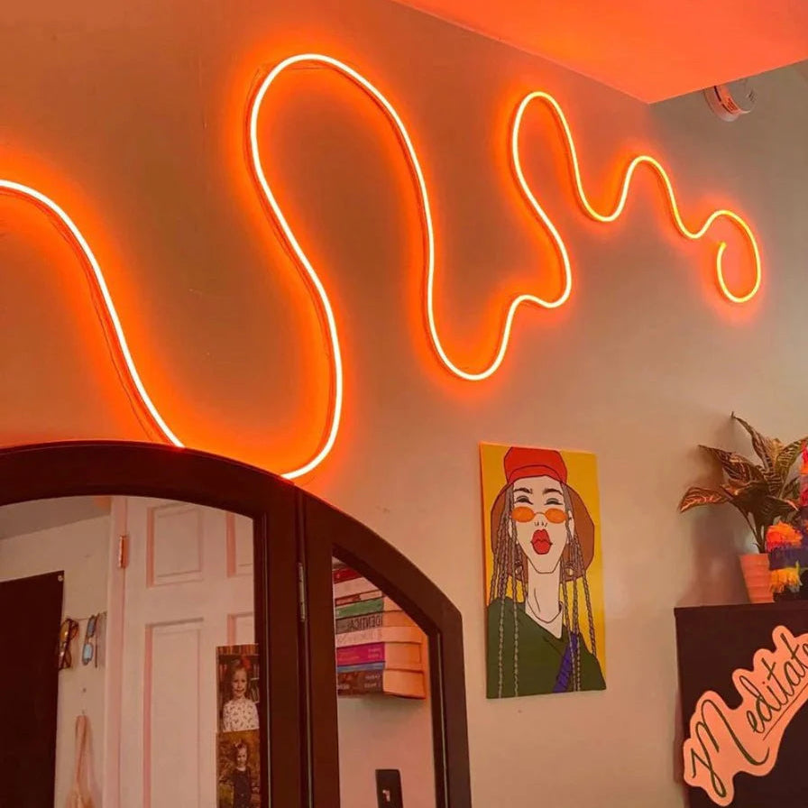 Neon sign on a wall with a mirror and artwork in the background