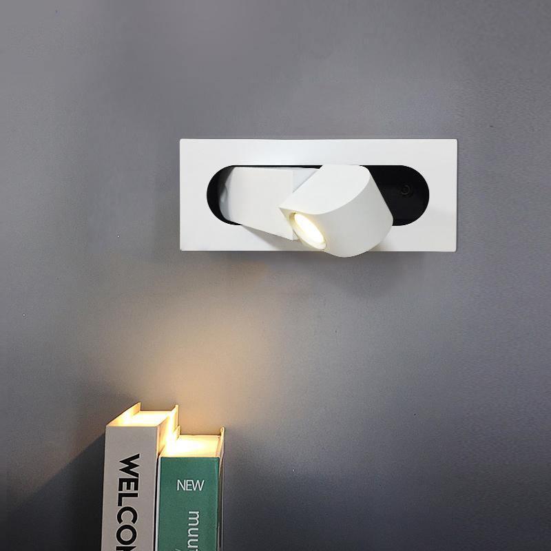 Modern wall-mounted light fixture on a gray wall with a book below.