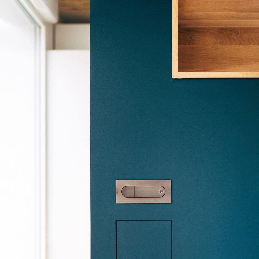Teal door with wooden handle and shelf in a room.