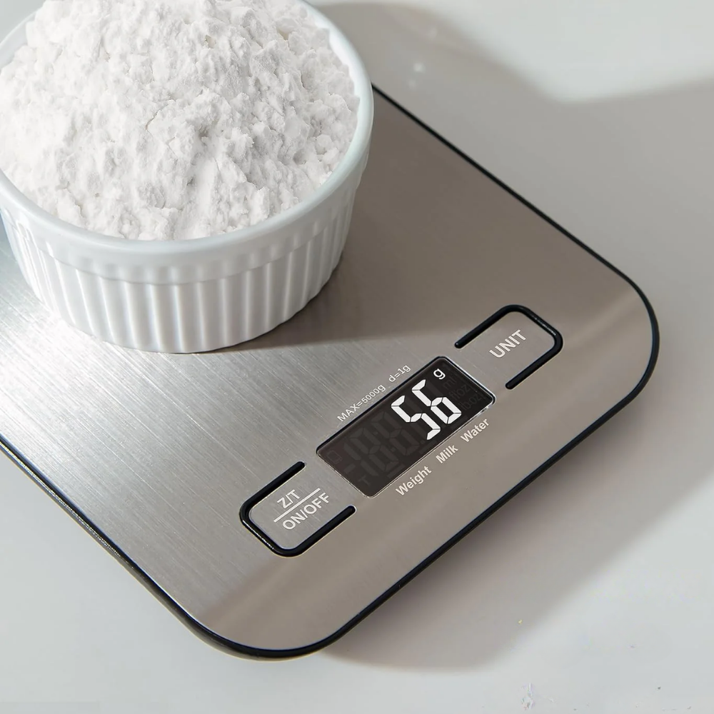 Digital kitchen scale with a bowl of flour on a white surface