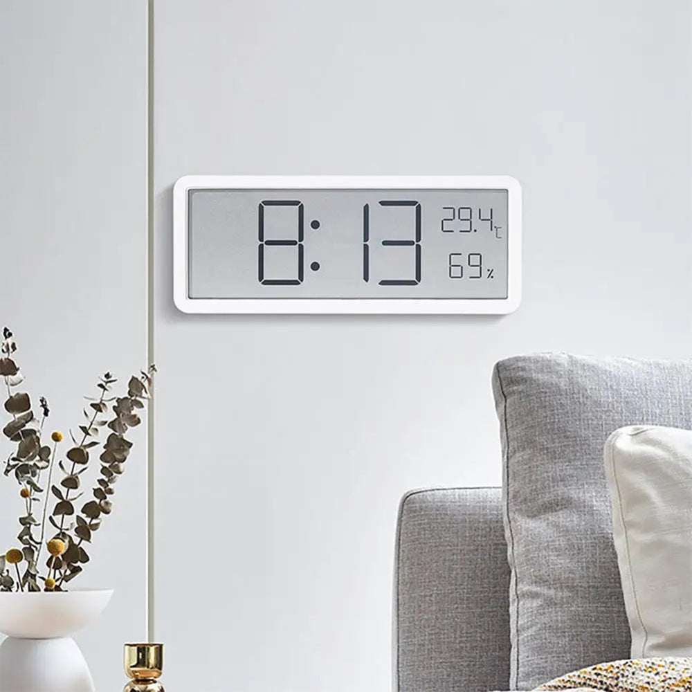 Digital clock on a wall with a living room setting