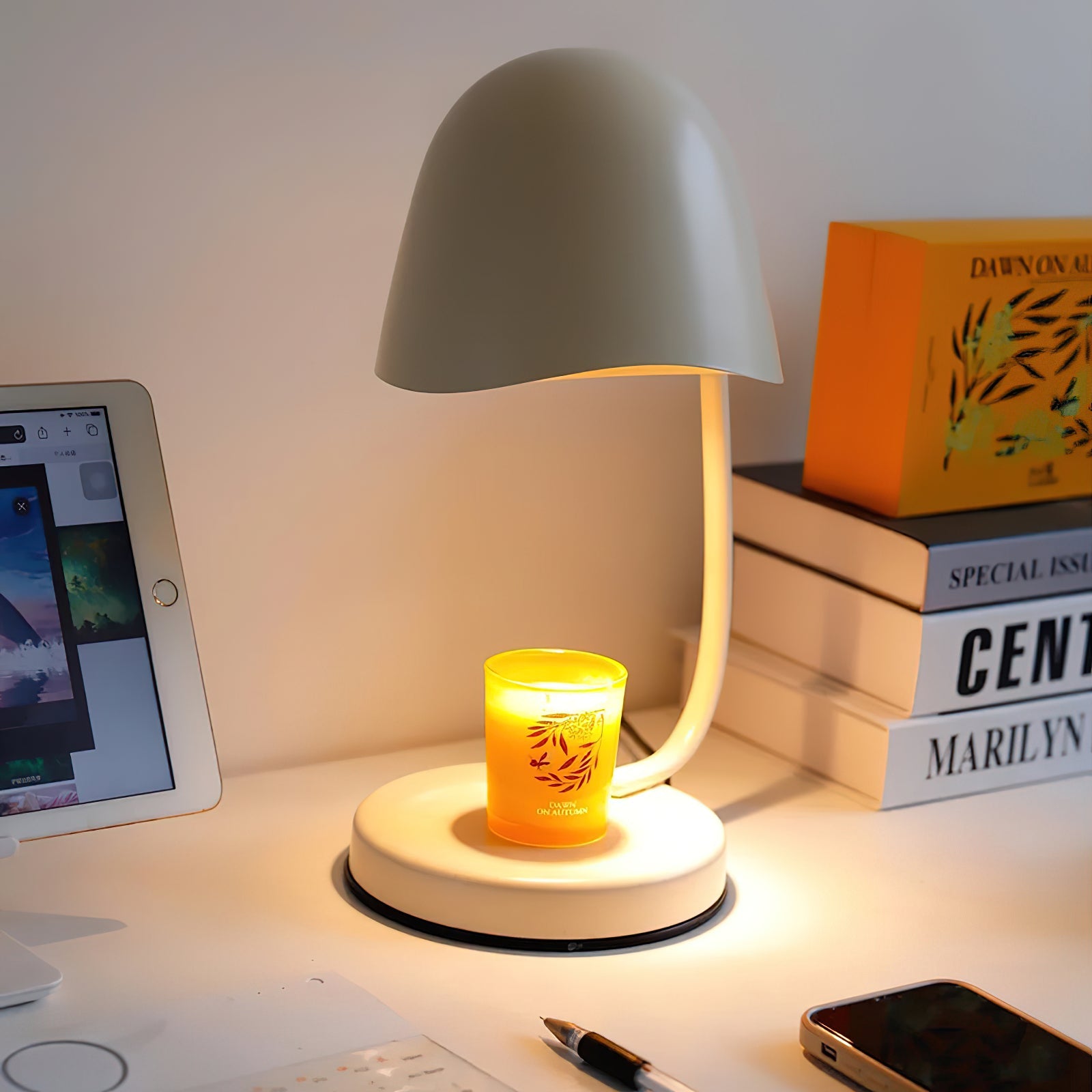 Small lamp with a candle on a desk next to a tablet and books