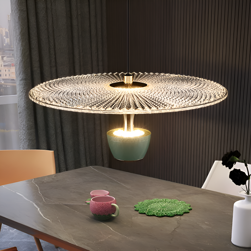 Modern pendant light hanging above a dining table with decor items.
