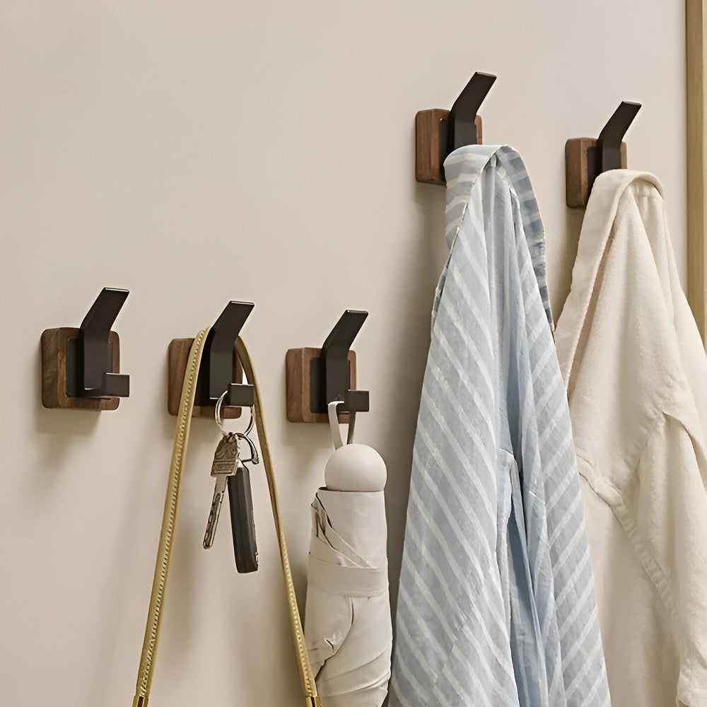 Wall-mounted hooks with clothes and bags on a light beige wall