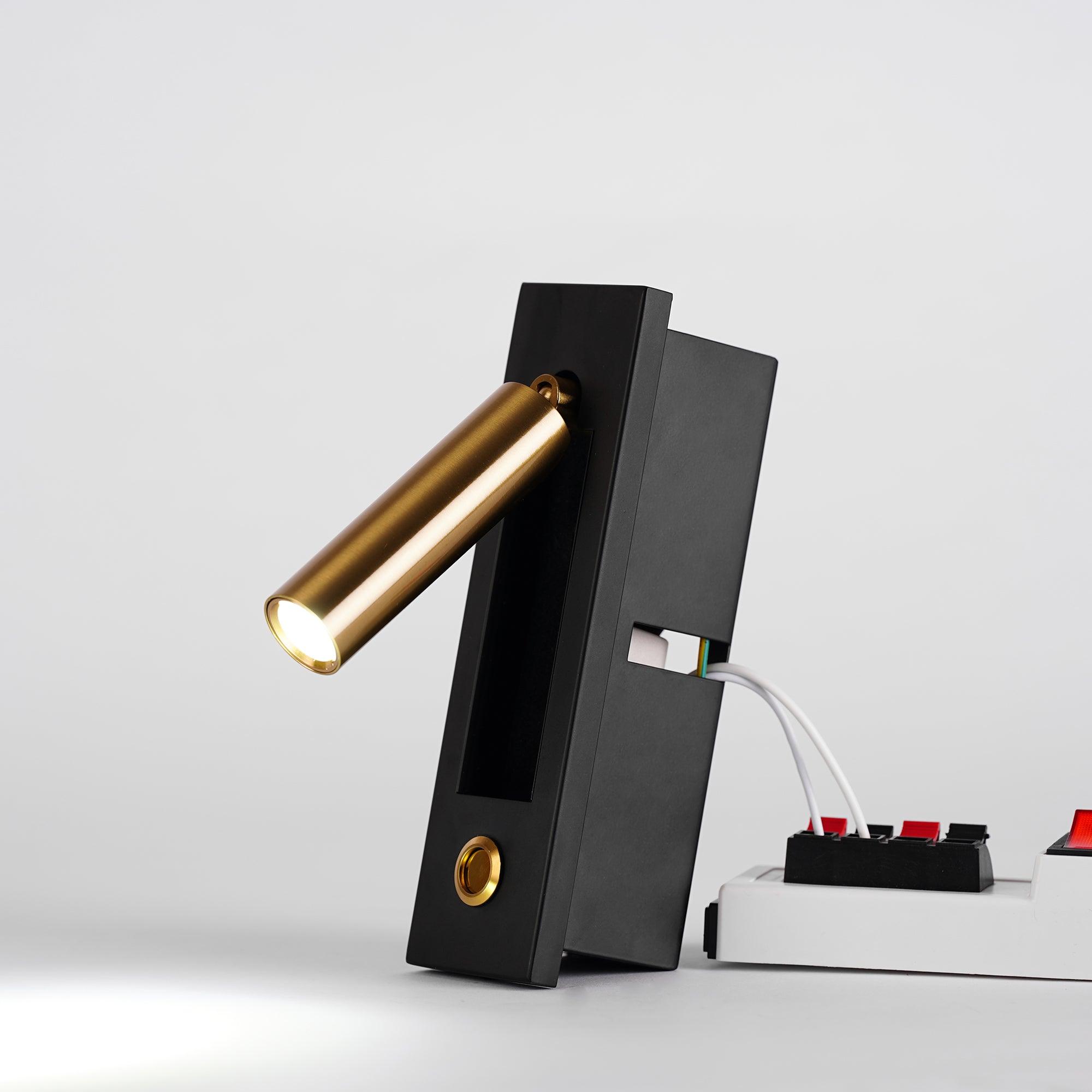 Modern black and gold desk lamp on a white surface with a neutral background