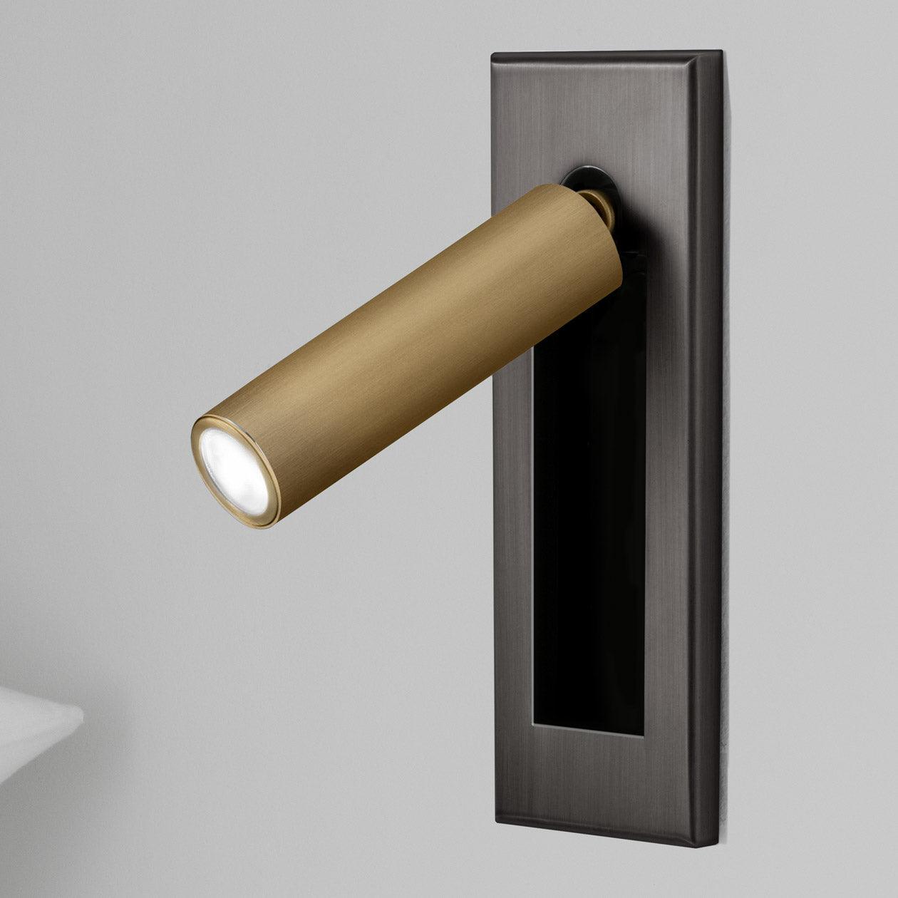 Wall-mounted light fixture with brass cylindrical design on a gray background