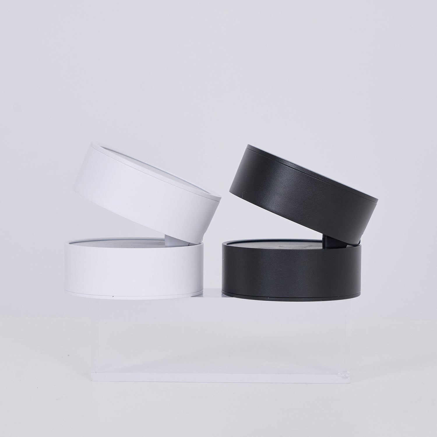 Two black cylindrical containers with clear lids on a light gray background