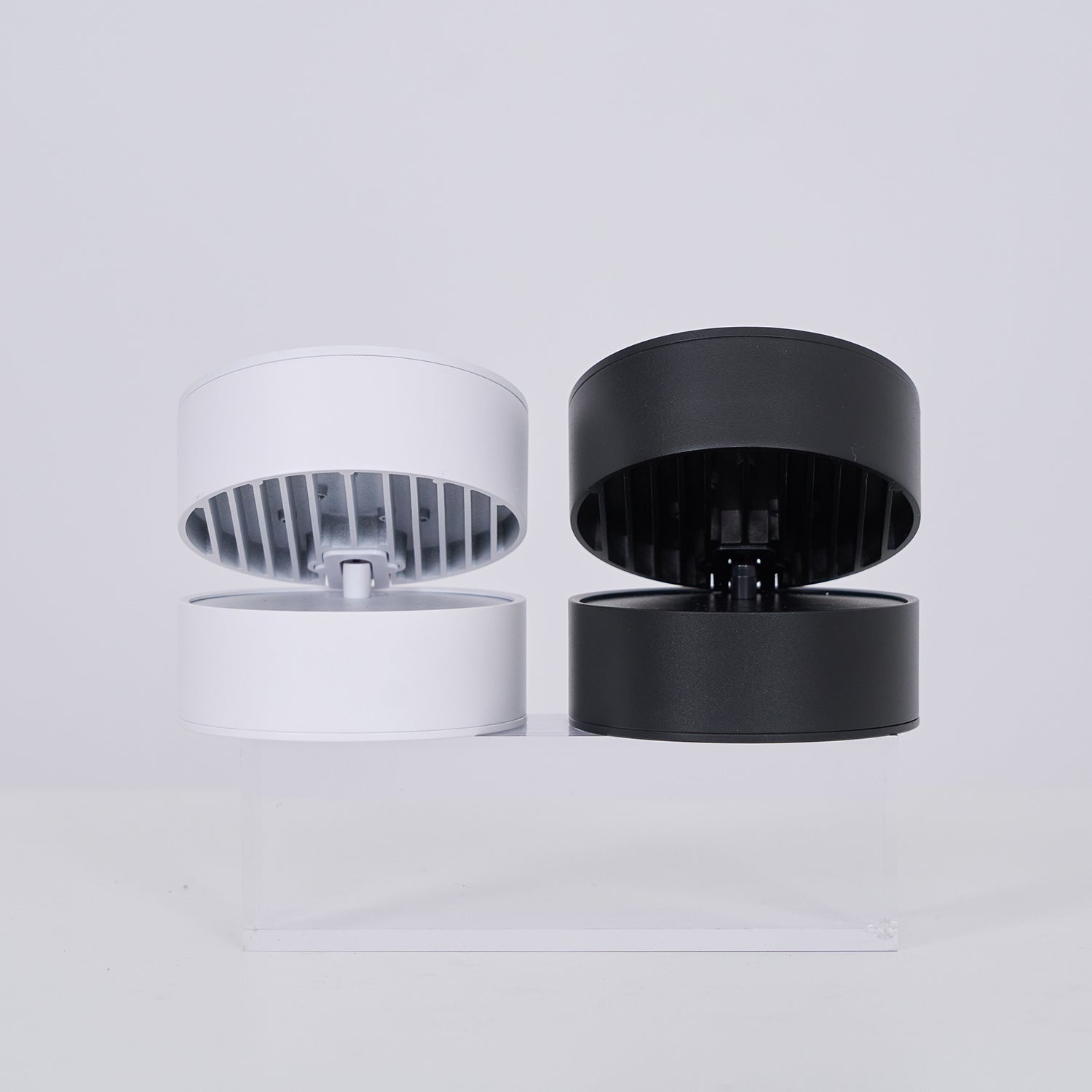 Two cylindrical light, one white and one black, on a light gray background.