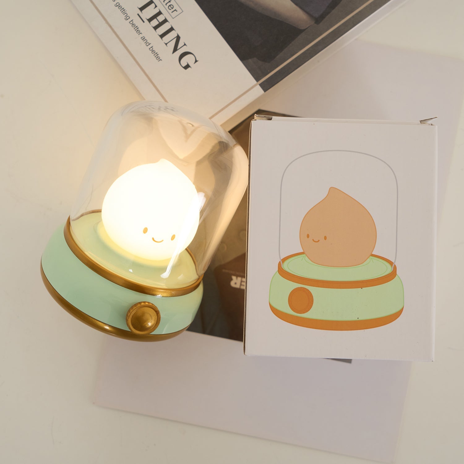 Small lamp with a cute design on a surface next to a card with a similar illustration.
