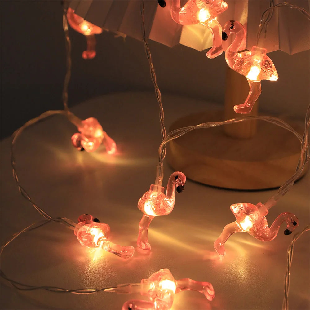 String lights shaped like flamingos on a reflective surface with a dark background
