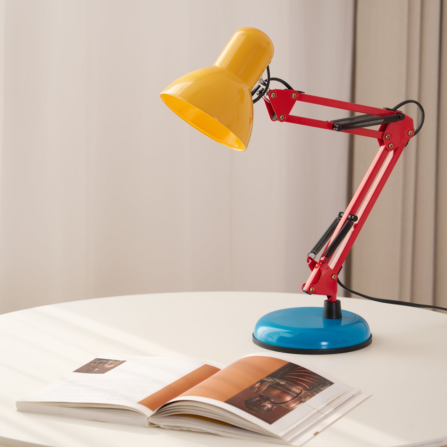 Colorful desk lamp with a yellow shade, red arm, and blue base on a white surface.