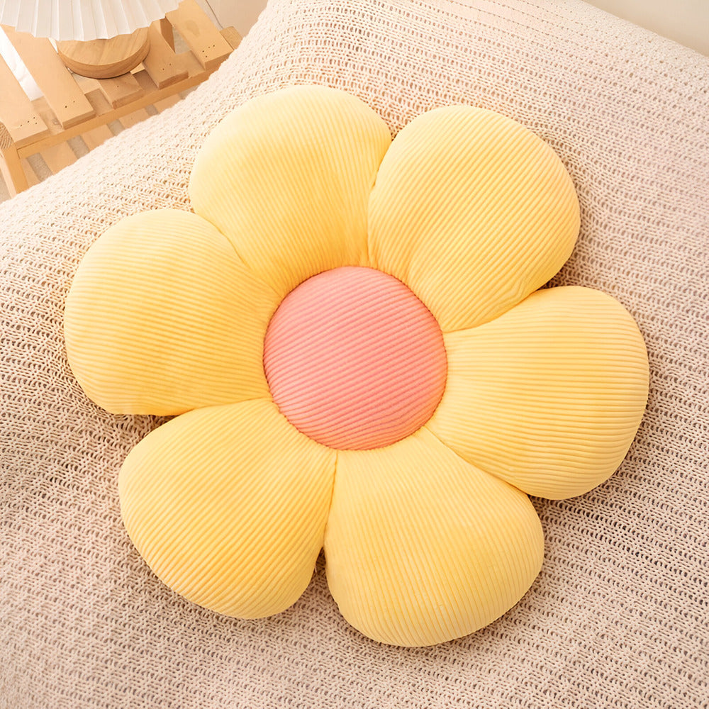 Yellow flower-shaped cushion with a pink center on a textured surface