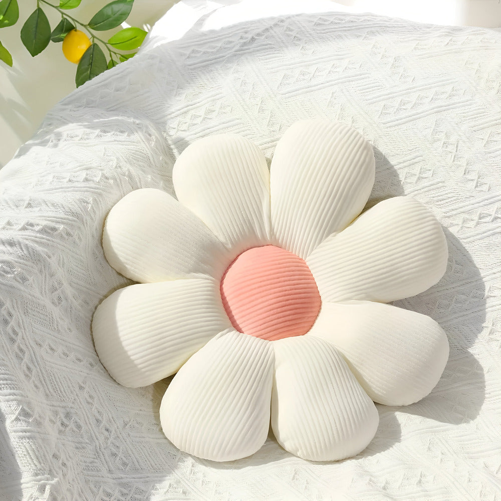 Flower-shaped cushion with white petals and a pink center on a textured surface.