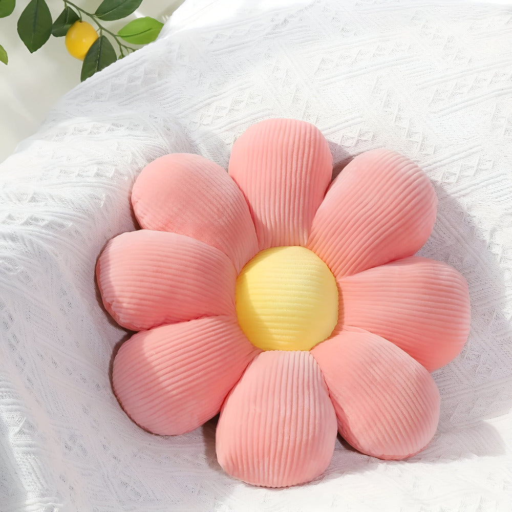 Pink flower-shaped cushion with a yellow center on a white textured surface.