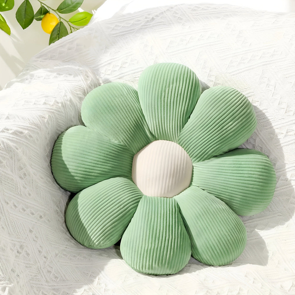 Green flower-shaped cushion on a white textured surface with a blurred natural background