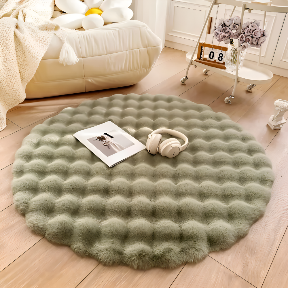 Round green rug on a wooden floor with a book and headphones on top, in a cozy room setting.